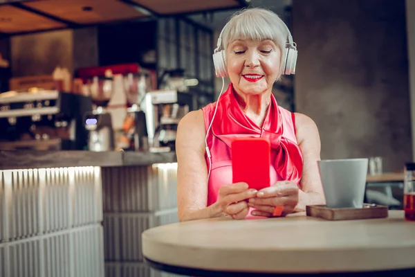 Mujer anciana encantada escuchando música en auriculares — Foto de Stock