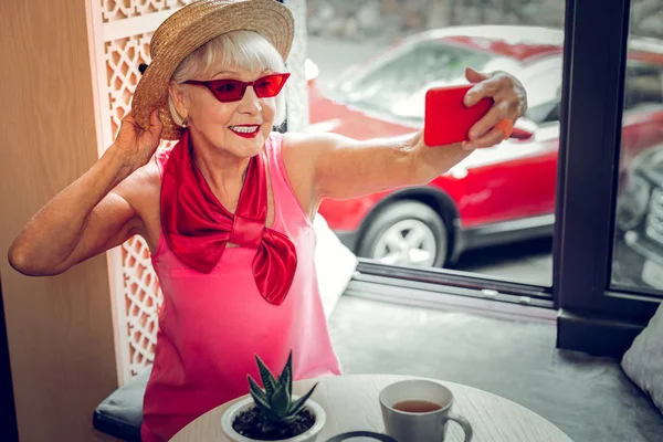 Радостная стильная пожилая женщина фотографирует на телефон — стоковое фото