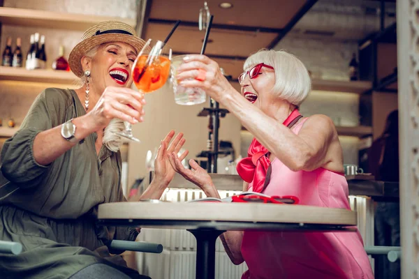 Bajo ángulo de mujeres felices positivas animando con bebidas — Foto de Stock