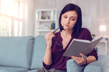 Elinde bir kitap tutan konsantre şık büyüleyici orta yaşlı bayan