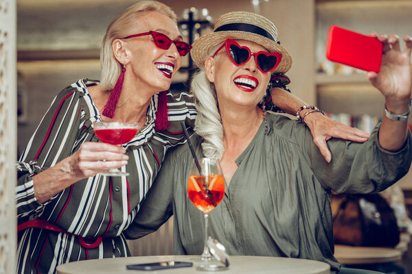 Радостные красивые стильные женщины, фотографирующиеся вместе
