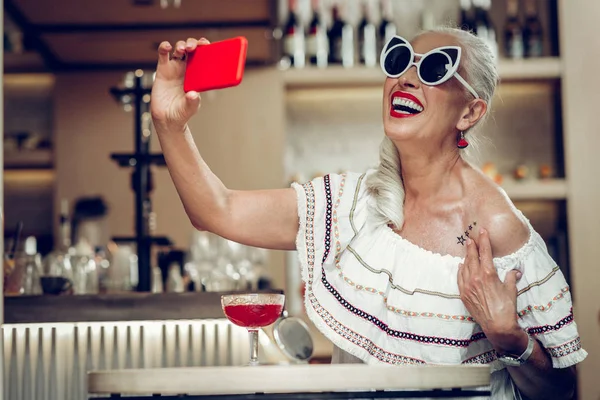 Радостная женщина, фотографирующая на смартфон — стоковое фото