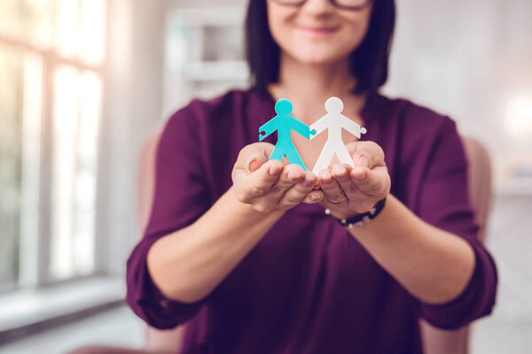 Взрослый восхитительный привлекательный менеджер держит в руках человеческие фигуры
