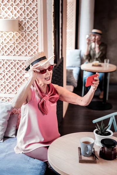 Vecchia signora attiva in visita elegante caffè e fare selfie — Foto Stock