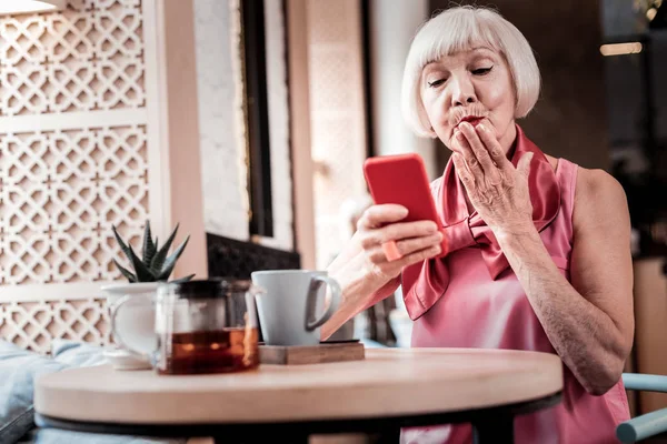 Rövid hajú szőke Senior nő, amelynek video chat az ő okostelefon — Stock Fotó