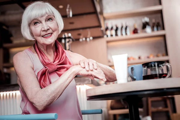 Rövid hajú idős nő, ragyogó smink gondoskodó kezét — Stock Fotó