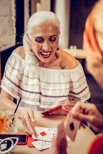 Excited long-haired senior woman with bright lipstick and white top — Stock Photo, Image