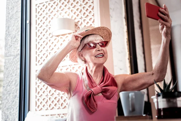Ухоженная старушка в соломенной шляпе делает фотографии — стоковое фото