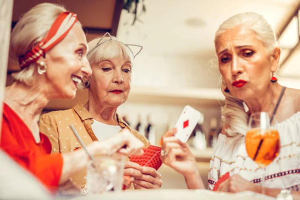 Αναστατωμένος μακριά μαλλιά ηλικιωμένη γυναίκα που δείχνει τις κάρτες της κατά τη διάρκεια παιχνίδι τζόγου — Φωτογραφία Αρχείου