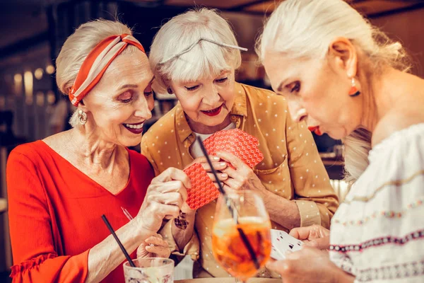 Fusk leende Senior Kvinna i hemlighet visar hennes kort — Stockfoto