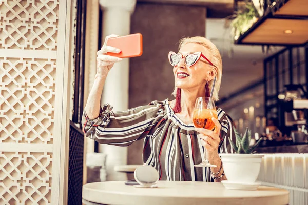 Femme blonde souriante portant de longs bijoux et des lunettes de soleil rouges — Photo