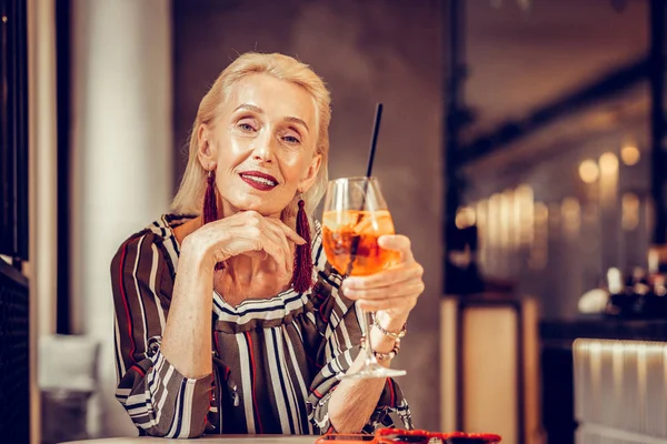Assez bien entretenu vieille femme posant avec un verre de cocktail — Photo
