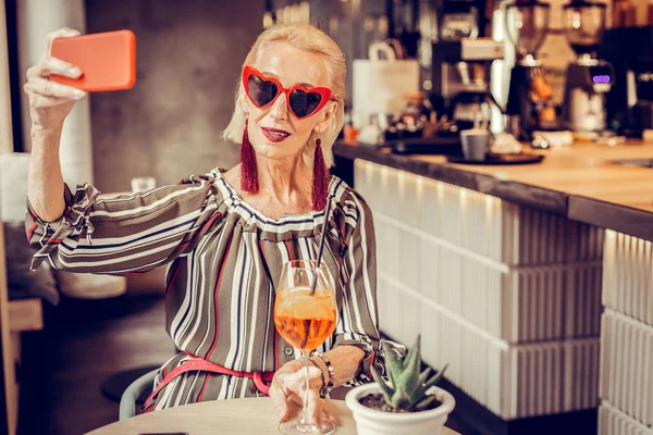 Современная красивая старушка в солнечных очках делает селфи — стоковое фото