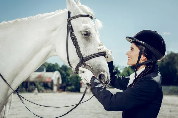 Agradable mujer bonita mirando el caballo blanco — Foto de Stock