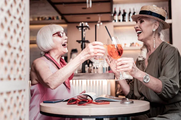 Aktive gut aussehende stilvolle Frauen, die Gläser mit Cocktails klappern — Stockfoto