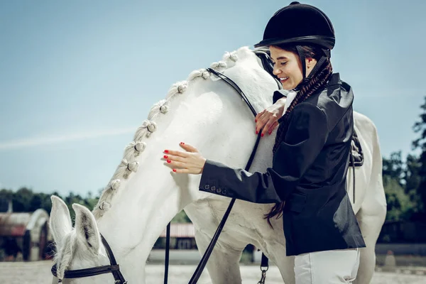 Joven alegre y positiva que se preocupa por su caballo — Foto de Stock