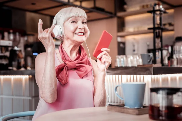 Активная старушка с широкой улыбкой жестикулирует, слушая музыку — стоковое фото