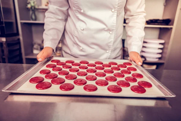 Confiseur professionnel tenant la plaque de cuisson dans les deux mains — Photo