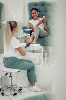 Gülümseyen koyu saçlı kadın müşteri rahat kadife koltukta yatarken