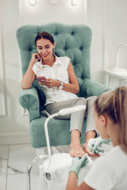 Yeşil koltukta dinlenen huzurlu görünümlü koyu saçlı kadın