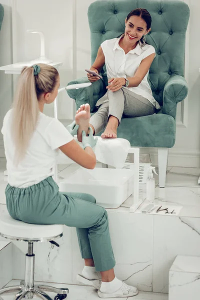 Client souriant aux cheveux bruns en chemisier blanc parlant à un maître attentionné — Photo