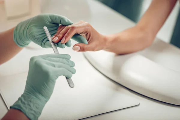 Professional skilled nail master wearing protective rubber gloves