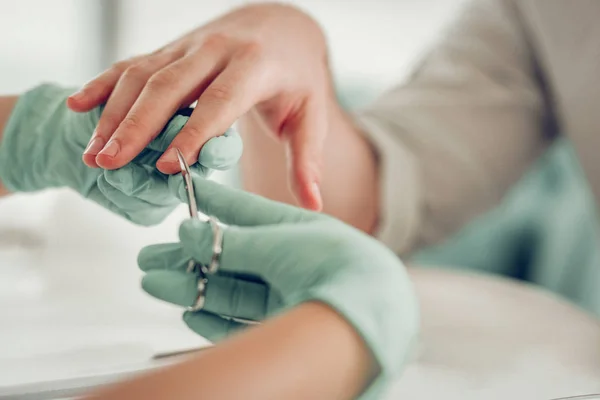 Nauwkeurige bekwame nagel Master in beschermende rubberen handschoenen die extra huid snijden — Stockfoto