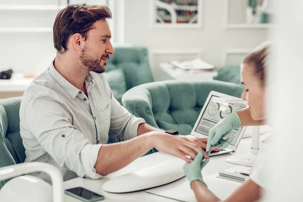 Gerichte bebaarde kerel in lichte shirt controle van informatie op een laptop — Stockfoto