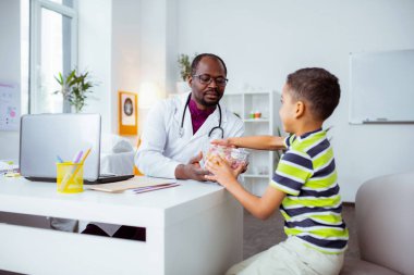 Koyu tenli doktor onun güzel oğluna tatlı şekerler ile kase veren