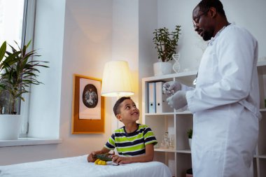 Enjeksiyon için çocuk doktoru beklerken sevimli çocuk oynuyor