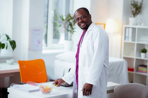 Cientista médico vestindo jaqueta branca em pé perto da mesa de trabalho — Fotografia de Stock