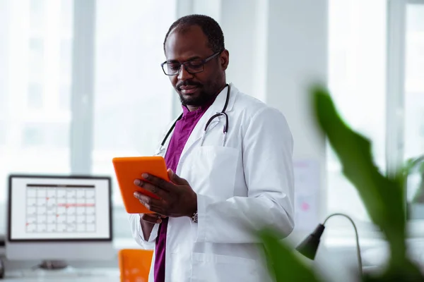 Científico médico sosteniendo tableta naranja trabajando en laboratorio — Foto de Stock