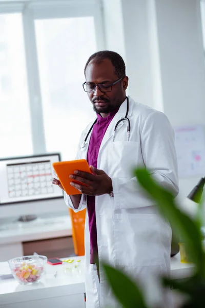 Médico usando tablet enquanto procura algumas informações — Fotografia de Stock