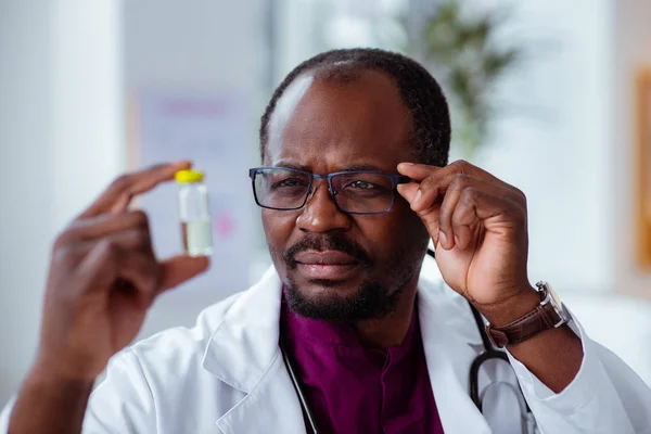 Médico usando óculos olhando para a ampola verificando o líquido — Fotografia de Stock