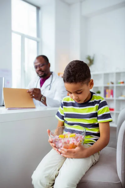 Hijo mirando caramelos visitando padre trabajando como médico en el hospital — Foto de Stock