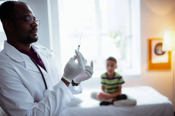 Pediatra con guantes que sostienen la jeringa antes de inyectar niño — Foto de Stock