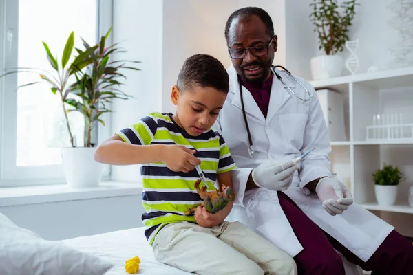 Lustige Patientin des Kinderarztes macht Spritze für Spielzeugdrachen — Stockfoto