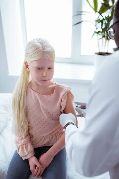 Blond meisje dragen roze blouse gevoel pijn krijgen injectie — Stockfoto