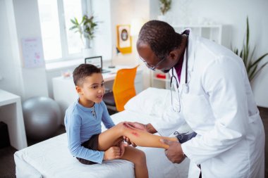 Çocuk doktoru bisikletten düştükten sonra çocuğun bacağına bakıyor