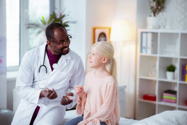 Doktor ona hapları verirken kız konuşurken gülümseyen