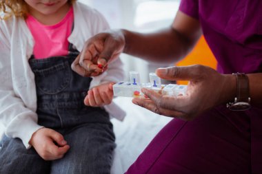 Küçük kız için hap veren koyu tenli doktor yakın çekim