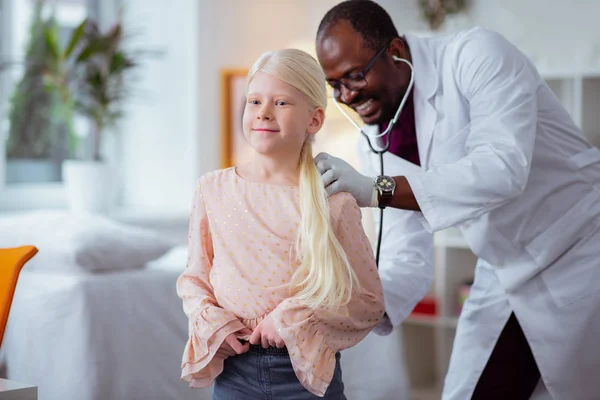 Дівчина посміхається під час відвідування педіатра за допомогою стетоскопа — стокове фото