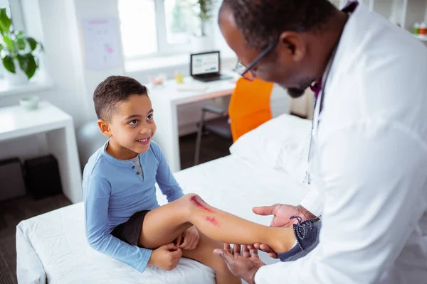 Lindo chico viniendo a pediatra después de rascarse la pierna — Foto de Stock
