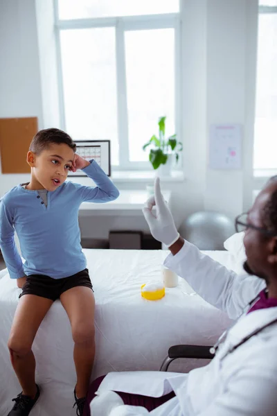 Söt skolpojke lyssnar på hans barnläkare uppmärksamt — Stockfoto
