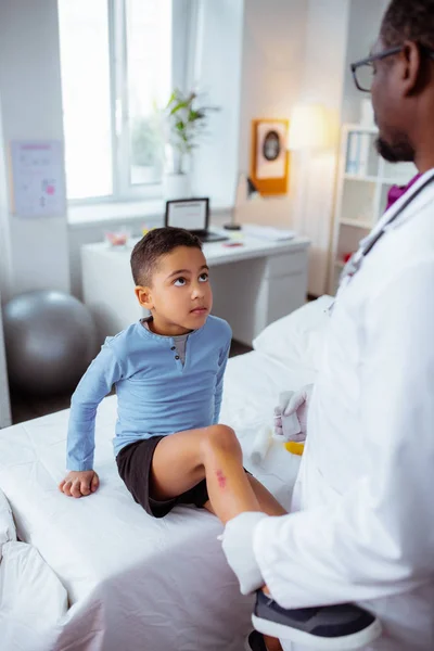 Pediatrician taking care of leg for boy after falling from bike — Stock Photo, Image