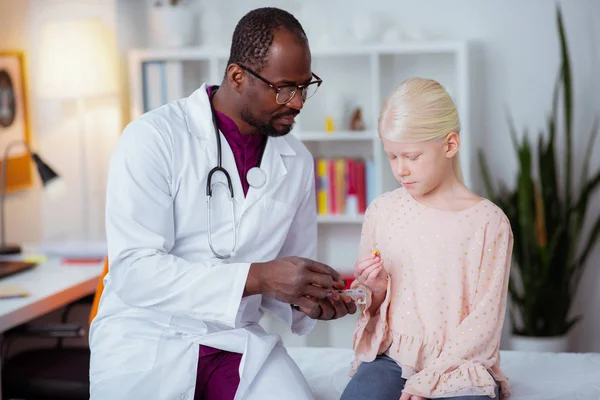 Angenehme dunkelhäutige Kinderärztin gibt kleinen Mädchen ein paar Pillen — Stockfoto