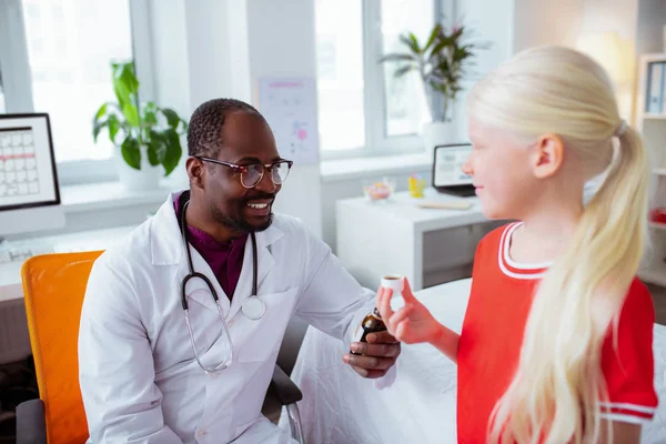 Médico profissional sorrindo dando xarope de tosse para menina doente — Fotografia de Stock