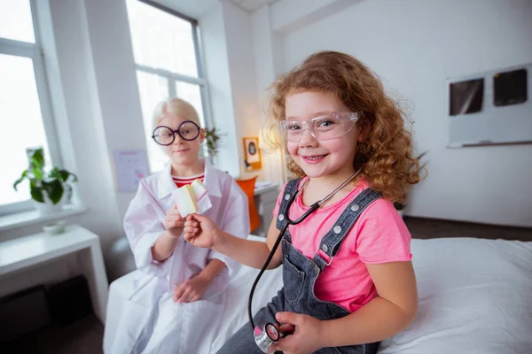 Funny girls wearing glasses eating glasses after playing together — Stock Photo, Image