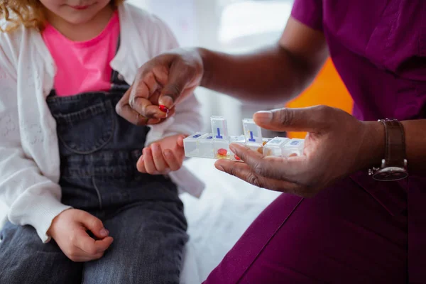 Primer plano del médico de piel oscura dando píldora para niña — Foto de Stock