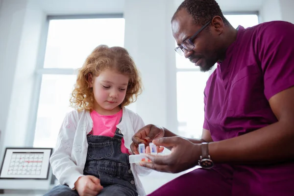 Carino piccola ragazza riccia prendendo pillole da piacevole pediatra — Foto Stock